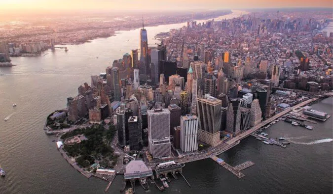 Aerial sunset view of Lower Manhattan skyline surrounded by rivers.
