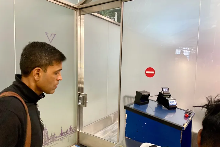 Man at a VIP One security checkpoint glass door with biometric scanning equipment at an airport.
