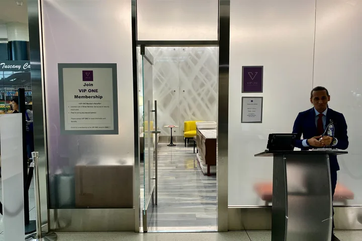 VIP One membership entrance at an airport with a suited staff member at a podium and lounge visible inside.