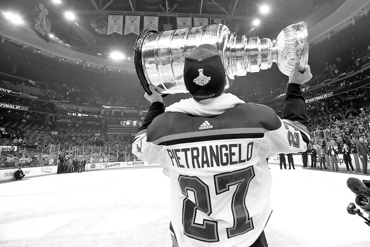 Hockey player Pietrangelo (#27) hoisting the Stanley Cup overhead on ice in an arena.