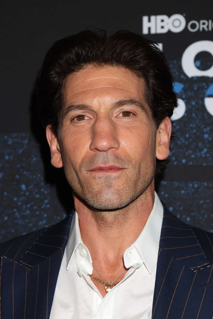 Jon Bernthal in a blue pinstripe blazer at an HBO event, smiling at a red carpet premiere.