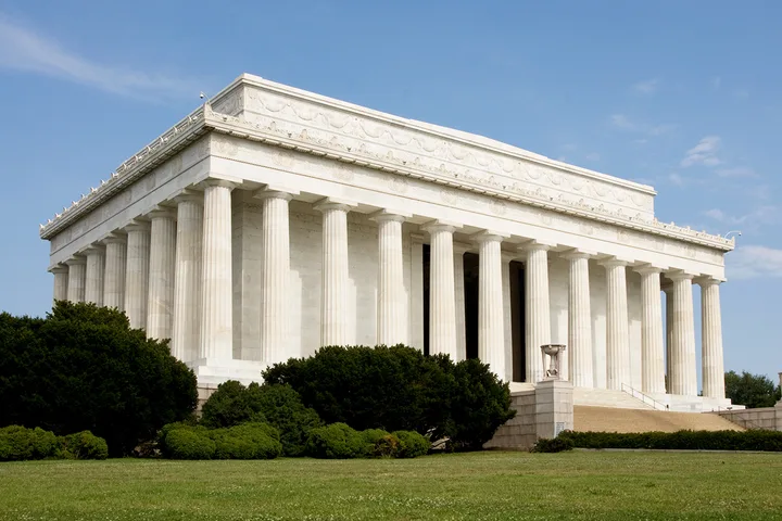Exterior view of the Lincoln Memorial with white marble columns on a sunny day.
