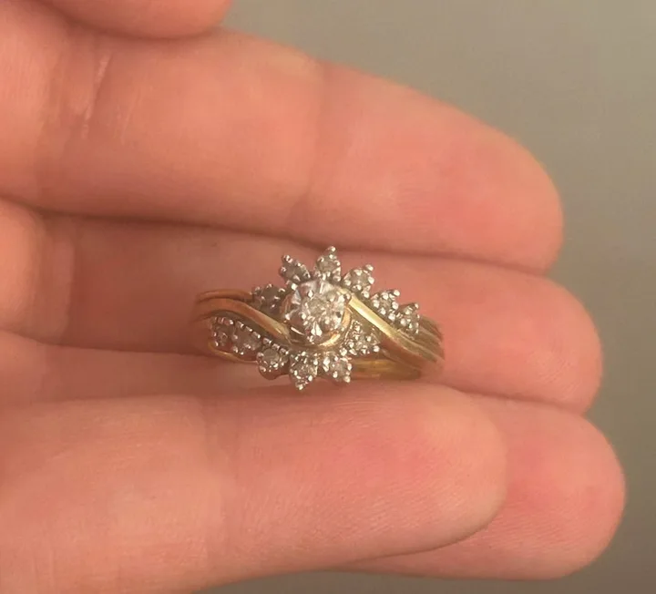 A vintage gold and diamond sunburst wedding ring set resting in an open palm.