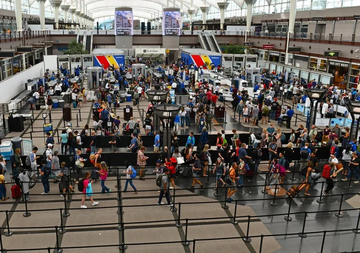 Overhead view of a massive, crowded airport security checkpoint with long lines of passengers.