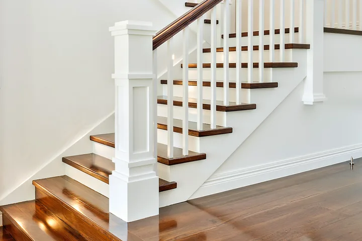 Elegant white and dark wood staircase with paneled newel post in a bright interior.
