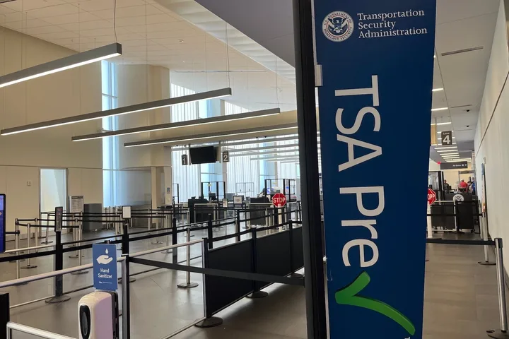 Empty TSA PreCheck security lanes at an airport with blue signage.