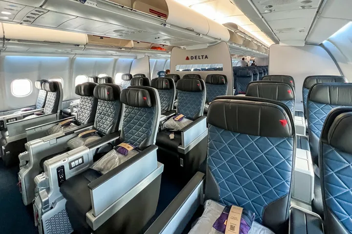Delta aircraft cabin showing business class seats on the left and Comfort+ quilted seats on the right.