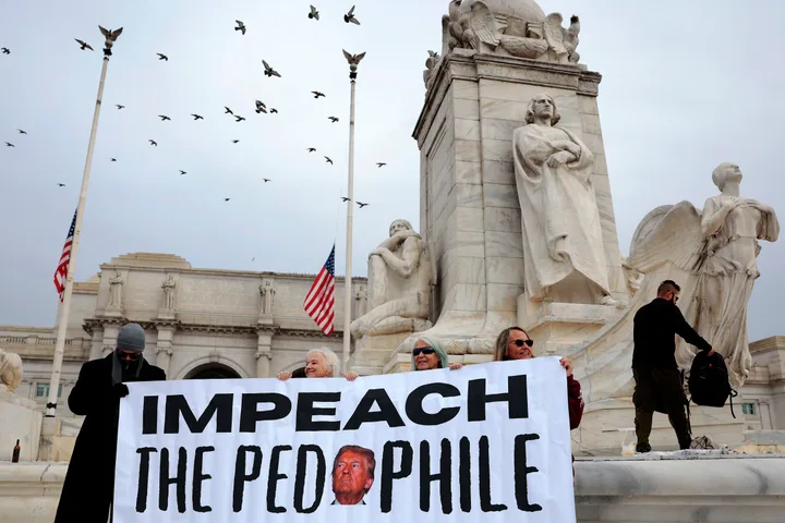 Protesters at a DC monument holding a large 'Impeach' banner with Trump's image in a crowd setting.
