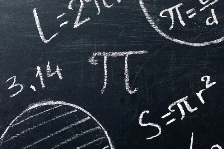 A blackboard covered in chalk-written pi symbol, 3.14, and circular geometry formulas.