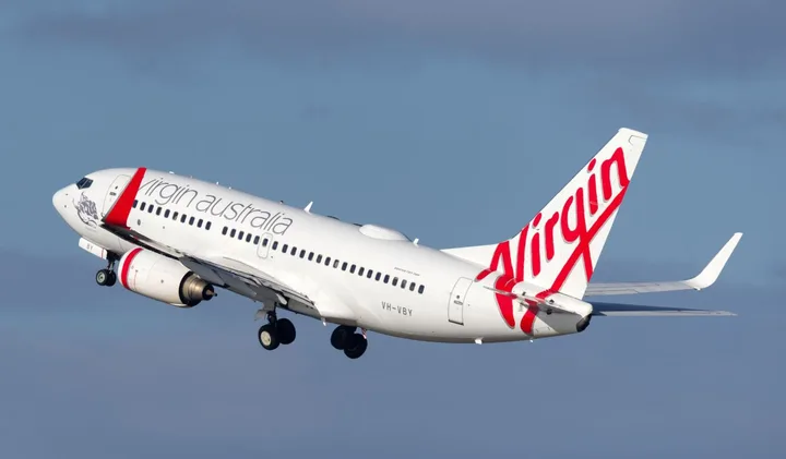 Virgin Australia Boeing 737 aircraft ascending into a blue sky shortly after takeoff.