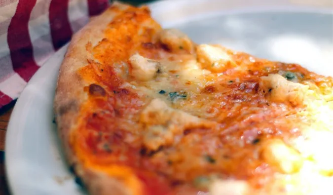 Close-up of a cheesy margherita pizza slice on a plate.