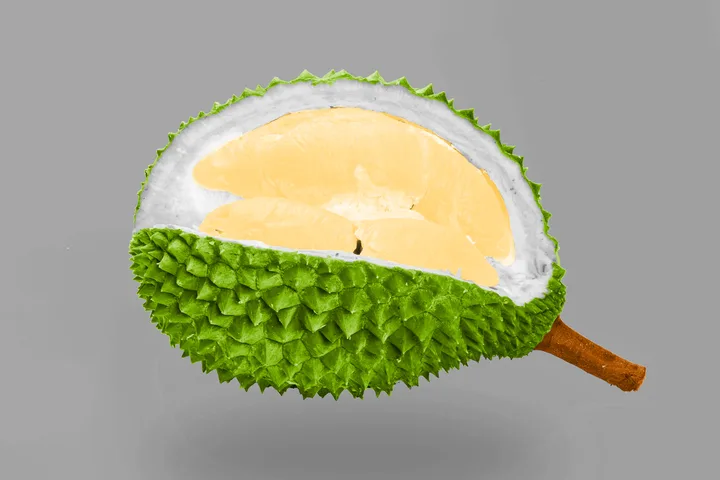 A halved durian fruit showing yellow flesh and spiky green exterior against a grey background.