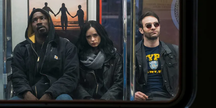 Three Marvel characters ride a subway train together, looking tense and serious.