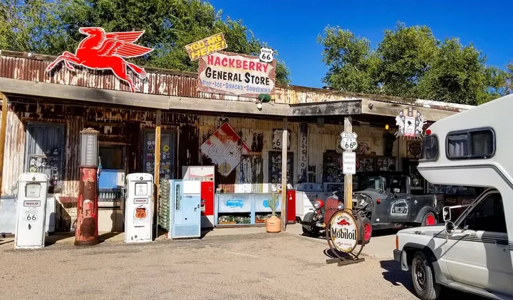 An RV parked beside the retro Hackberry General Store on Historic Route 66 under blue sky.
