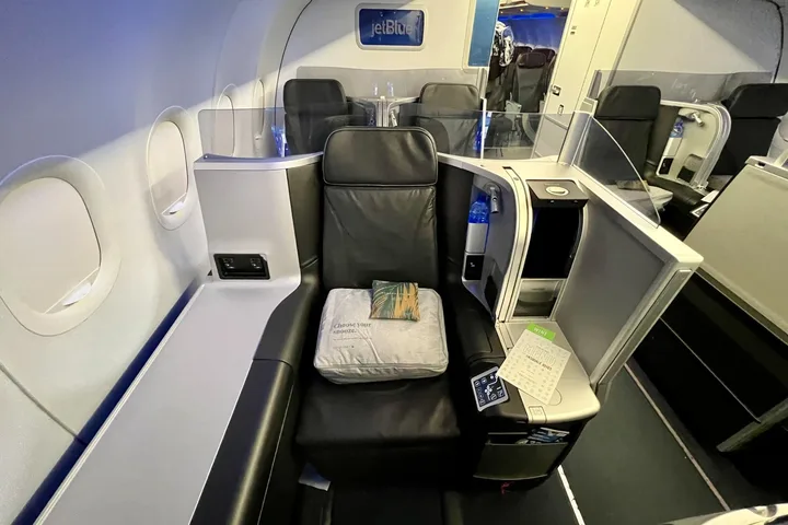 JetBlue Mint business class private suite with leather seat, pillow, and amenity kit.