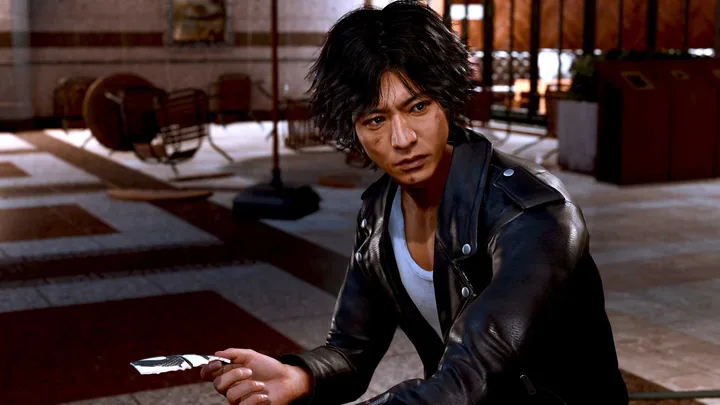 Judgment game protagonist Takayuki Yagami crouching in a grand interior hall, holding an item.