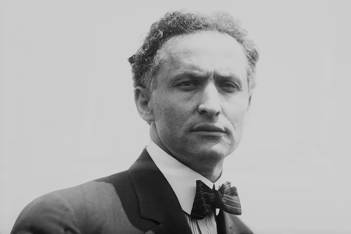 Vintage black and white portrait of a serious-looking man in a suit and bow tie.