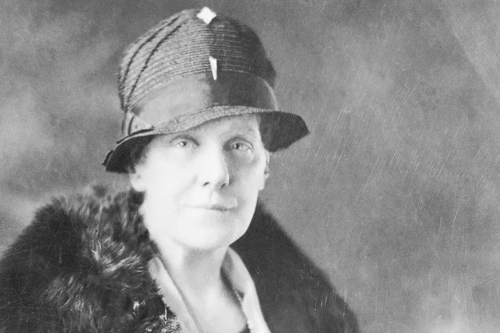 Vintage black-and-white portrait of a woman in a cloche hat with a serious expression.