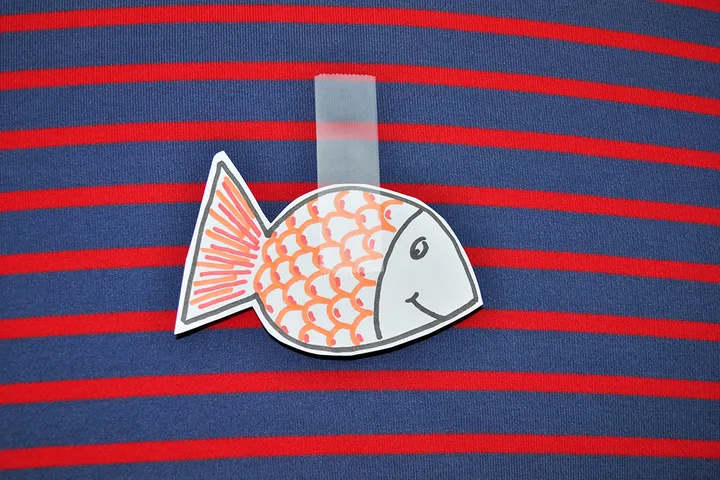 Paper fish cutout taped to a striped shirt, the classic April Fools' prank.