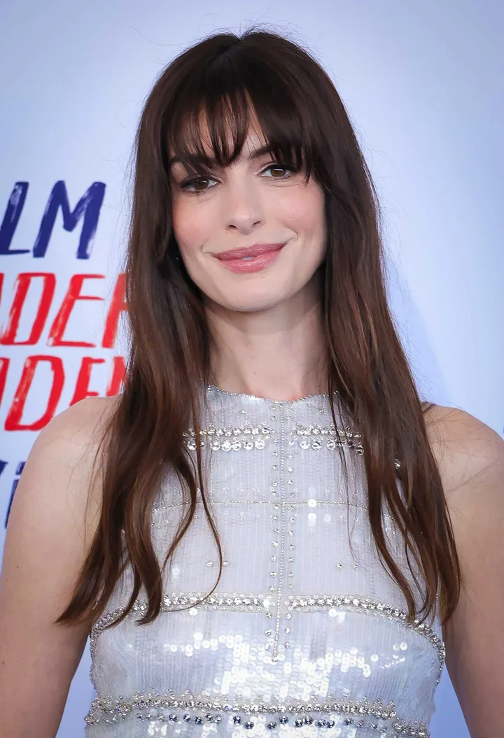 Dark-haired woman in a sequined dress smiling at a film premiere event.