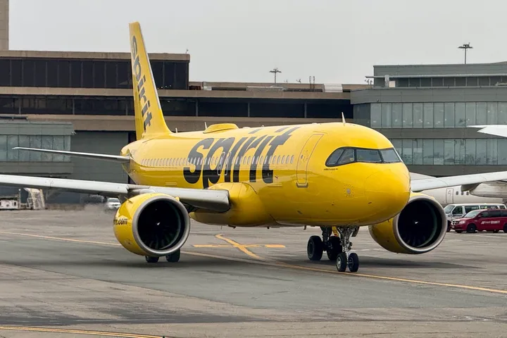 A bright yellow Spirit Airlines aircraft taxiing on an airport tarmac.