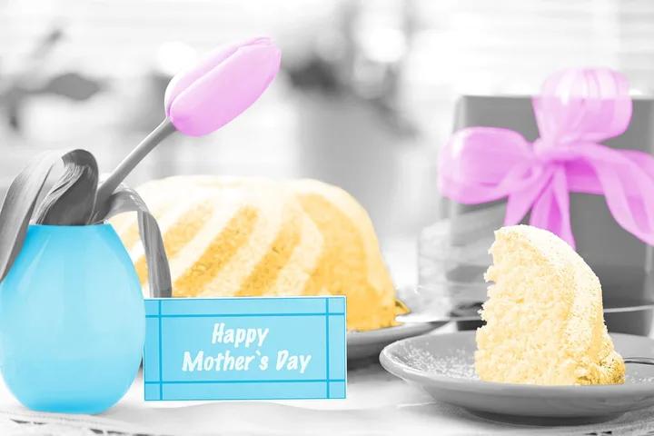 Mother's Day themed table setting with cake, tulip, gift box, and a 'Happy Mother's Day' card.